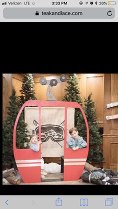 two children are sitting in a red tram with christmas trees behind them and an advertisement for teak and lace