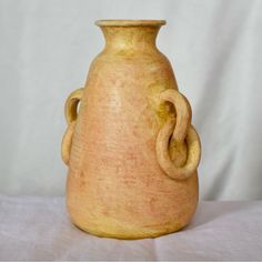 a small vase sitting on top of a white cloth covered table next to a wall