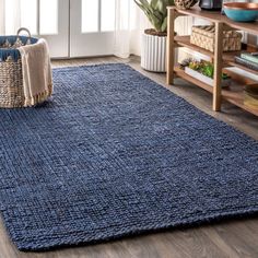 a blue rug in the middle of a living room with a basket on the floor