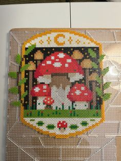 there is a cross stitch picture in the shape of a mushroom with mushrooms on it