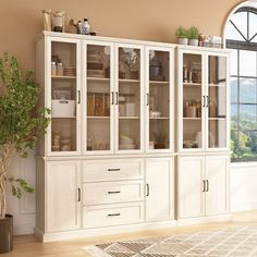 a large white bookcase with glass doors and drawers in the middle of a room