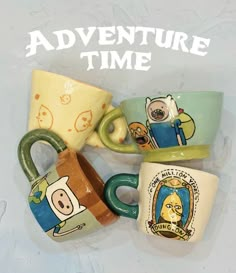 three coffee mugs with adventure time designs on them