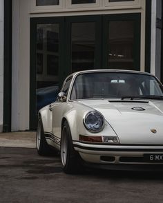 an old white porsche parked in front of a building