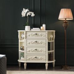 a white dresser sitting next to a lamp in a room