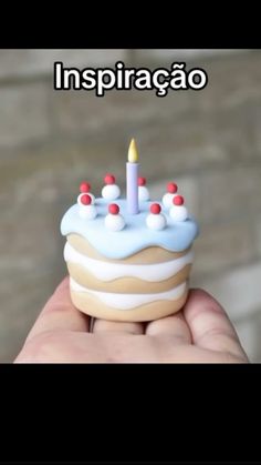 a hand holding a small birthday cake with candles on it's top and the words inspiracao written in spanish