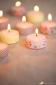 many lit candles sitting on top of a table next to cupcakes and candy wrappers