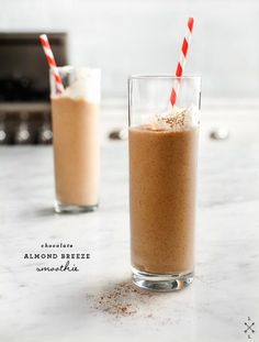 two glasses filled with chocolate milkshakes on top of a counter