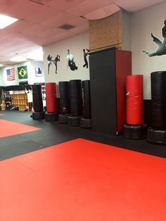 an indoor gym with red mats and black barrels