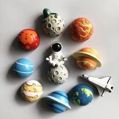 an assortment of small toy planets sitting on top of a white surface with a space shuttle in the middle