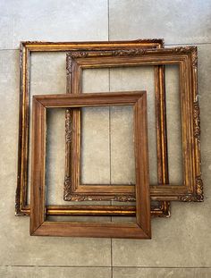 three wooden frames sitting next to each other on the floor in front of a wall