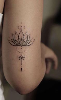 a woman's leg with a lotus tattoo on the back of her arm and an arrow