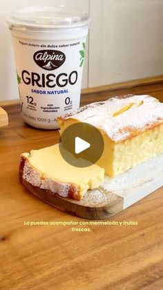 a piece of cake sitting on top of a wooden table next to a container of yogurt