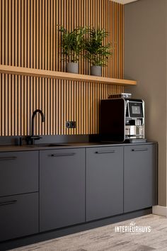 a kitchen area with a coffee maker, microwave and plants on the wall above it