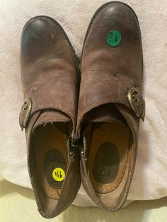 a pair of brown shoes sitting on top of a bed