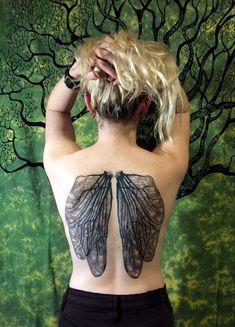 the back of a woman with tattoos on her upper and lower torso, showing an insect wing