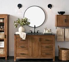 a bathroom with wooden cabinets and a round mirror above the sink, along with baskets on the floor