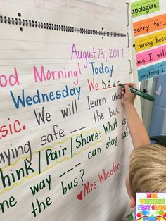 a child writing on a whiteboard with words written in different colors and styles,