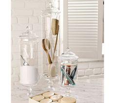 an assortment of personal care items on a marble counter with white brick wall in the background