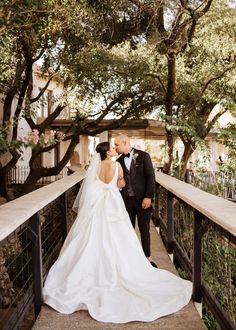 a bride and groom kissing on a bridge