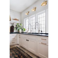 a white kitchen with black counter tops and gold faucets on the windowsill