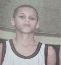 a young boy wearing a white and black basketball uniform looking at the camera with an intense look on his face