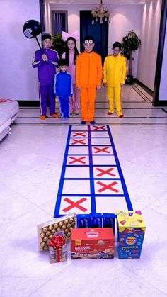 three people in colorful costumes standing next to a game board with candy and candies on it