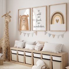 a nursery room with three pictures on the wall and two stuffed animals hanging above it