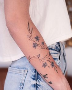 a woman's arm with flowers on it and leaves in the middle of her arm