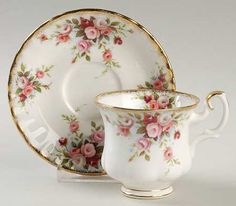 an antique tea cup and saucer with pink roses on it, sitting side by side