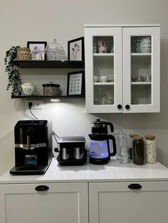 the coffee maker is sitting on the counter next to the cupboards with cups and other items