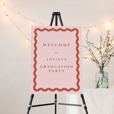 a welcome sign for a graduation party on an easel with string lights in the background