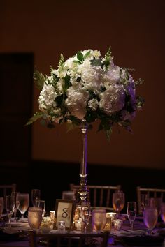 a tall vase filled with white flowers on top of a table