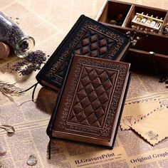 two brown leather books sitting on top of a table next to some dried lavenders