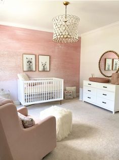 a baby's room with pink walls, white furniture and a chandelier