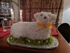 a cake made to look like a sheep sitting on top of a table with candles in the background