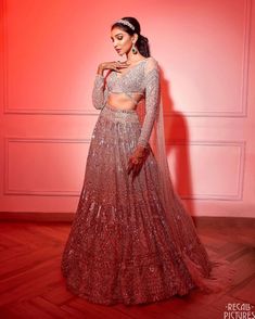 a woman in a red and silver lehenga with her hands on her hips