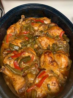 a pan filled with chicken and peppers on top of a stove