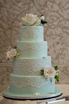 a three tiered wedding cake with white flowers on the top and green icing