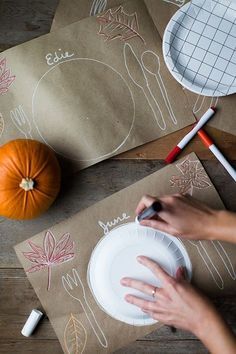 the person is cutting paper with scissors and other crafting supplies on the table next to pumpkins