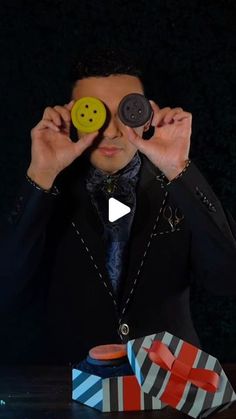 a man in a suit holding up two buttons to his eyes and looking through them