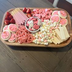 a wooden tray filled with cookies, marshmallows, strawberries and other treats