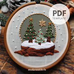 an embroidered christmas scene with trees and snow on the ground, surrounded by pine cones