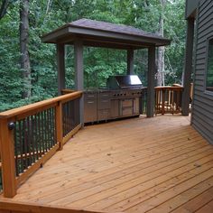 a wooden deck with an outdoor grill and gazebo