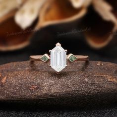 an emerald and diamond ring sitting on top of a piece of wood