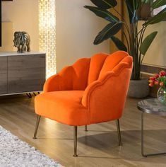 an orange chair sitting on top of a hard wood floor next to a glass table