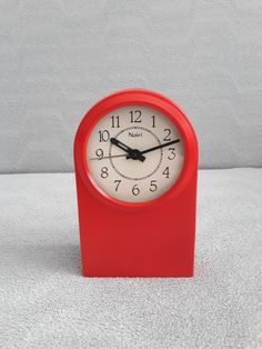 a red clock sitting on top of a white table