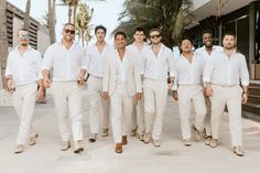 a group of men standing next to each other wearing white suits and shades on their faces