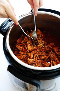 someone is spooning some food out of the slow cooker