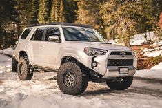 a white toyota 4runner is driving through the snow