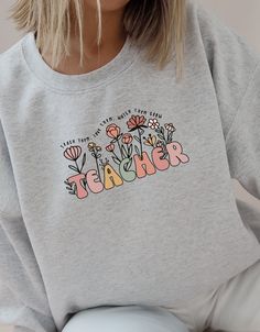 Teacher T-shirt with Retro Inscription and Inspirational Quote - Ideal Gift **Description : Discover the perfect t-shirt for teachers, decorated with the inscription "TEACHER" in retro flowers and the inspirational quote "TEACH THEM, LOVE THEM, WATCH THEM GROW". Comfortable and stylish, this sweatshirt is the perfect gift to thank a teacher at graduation or for any other occasion. Keywords: teacher gift, teacher t-shirt, cotton wool, teacher graduation, thank you gift, retro inspiration, flowers Spring Graphic Print Sweatshirt For School, Graphic Print Sweatshirt For School In Spring, Spring Graphic Print School Sweatshirt, Fall Cotton Sweatshirt For Teacher Appreciation, Teacher Sweater, Teacher Graduation, Retro Inspiration, Graduating Teacher, Teacher Sweatshirt